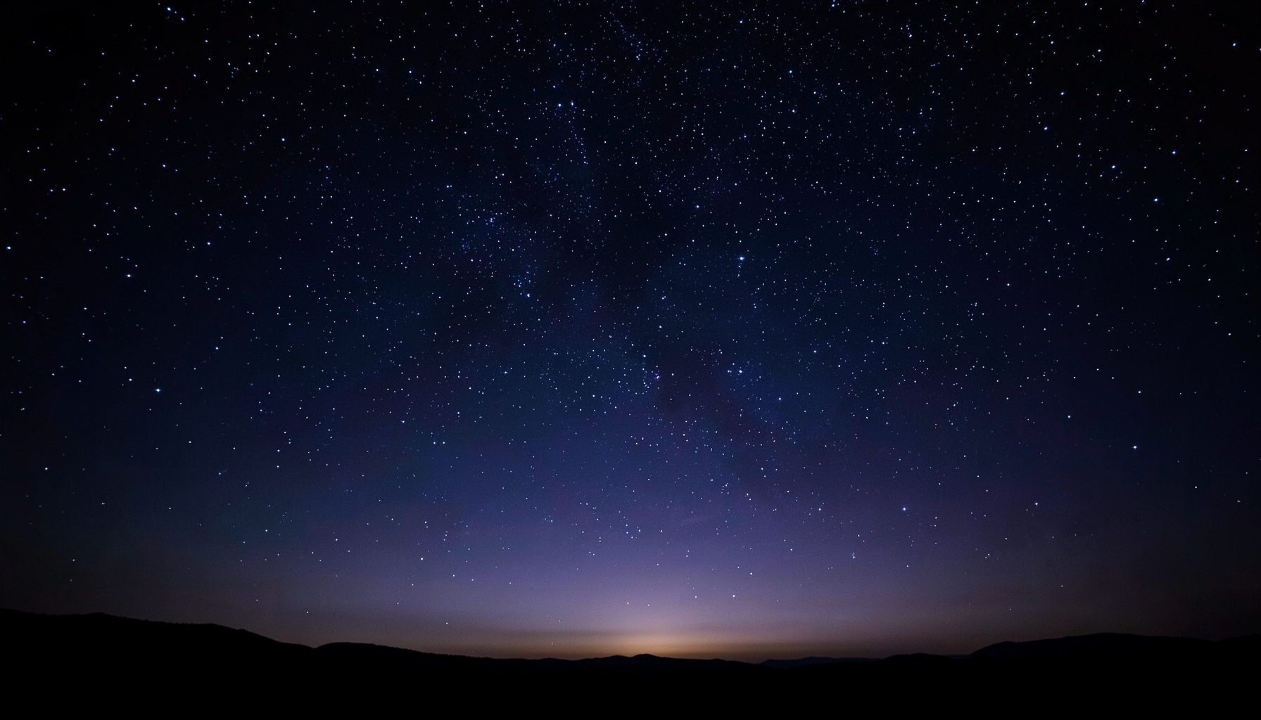 Cielo estrellado en tonos azul oscuro y violeta, con una luz tenue en el horizonte que evoca calma y reflexión.
